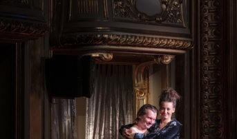Kliknij by powiększyć zdjęcie. Alternatywny opis zdjęcia: Ujęcie na dwa balkony teatralne. Na najniższym aktorka siedzi na kolanach aktora. Obejmują się. Są uśmiechnięci. Nad nimi, o drugi balkon opiera się kolejna para - aktorka z aktorem. Rozmawiają.