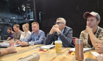 Pięciu aktorów i aktorką siedzą na krzesłach przy stolikach na Dużej Scenie. Trwa próba. Są zamyśleni.