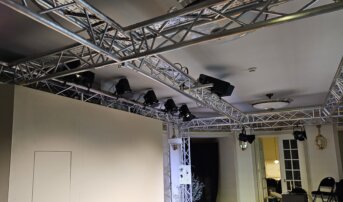 Rząd reflektorów zamontowanych na aluminiowej konstrukcji w teatrze.