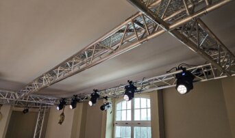 Rząd reflektorów zamontowanych na aluminiowej konstrukcji w teatrze.