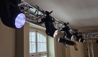 Rząd reflektorów zamontowanych na aluminiowej konstrukcji w teatrze.