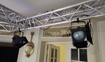 Rząd reflektorów zamontowanych na aluminiowej konstrukcji w teatrze.