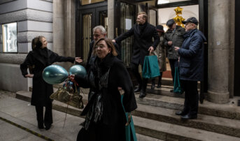 Goście wychodzą a budynku teatru. Trzymają w dłoniach upominki i balony