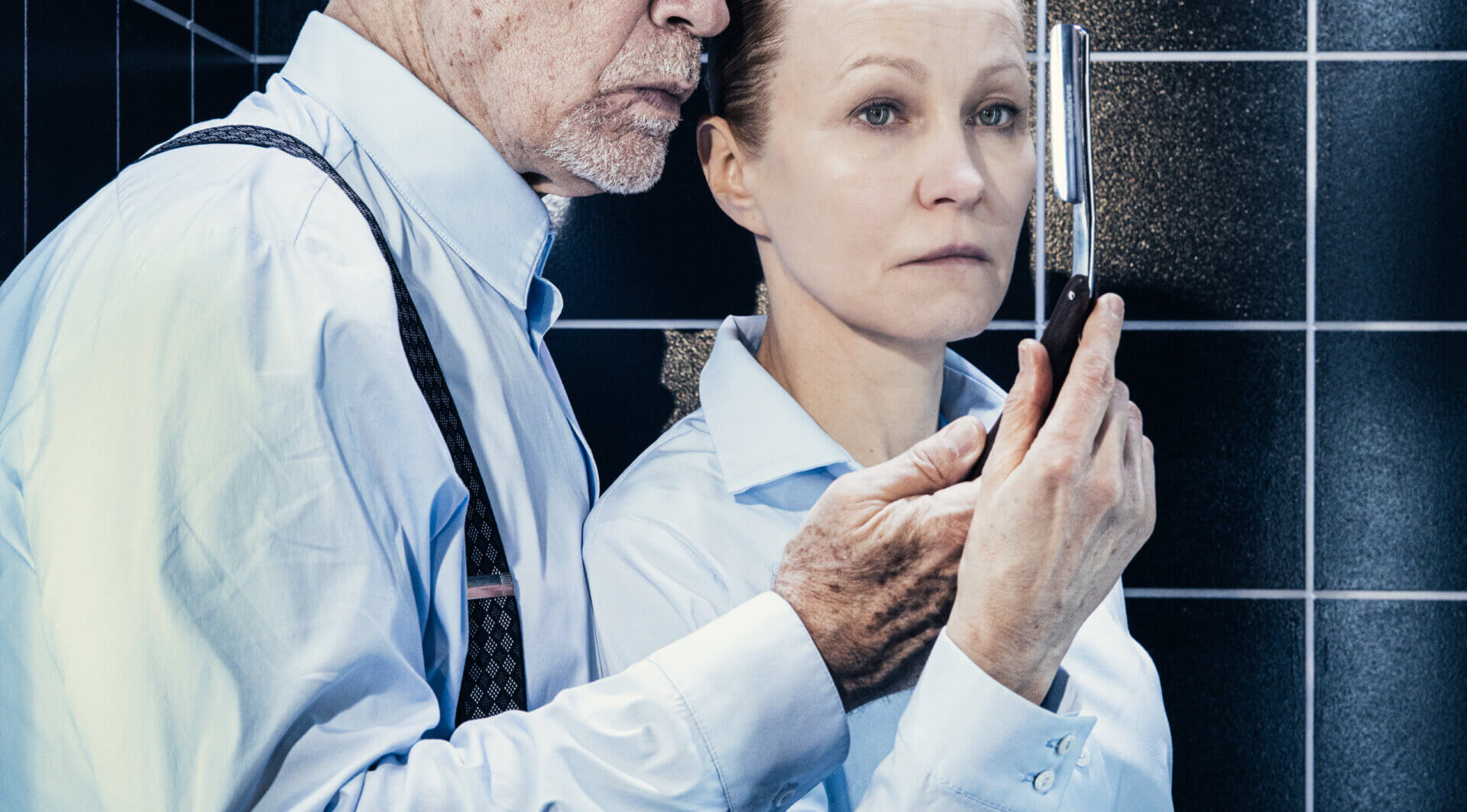 Kliknij by powiększyć zdjęcie. Alternatywny opis zdjęcia: Malkovich i Dapkunaite stoją blisko siebie pod deszczownicą. Ona trzyma lusterko, w którym odbija się ich twarz. Oboje mają poważne wyrazy twarzy.